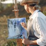 How to Find the Artist Residency That's Right for You. A woman paints a beautiful landscape painting.