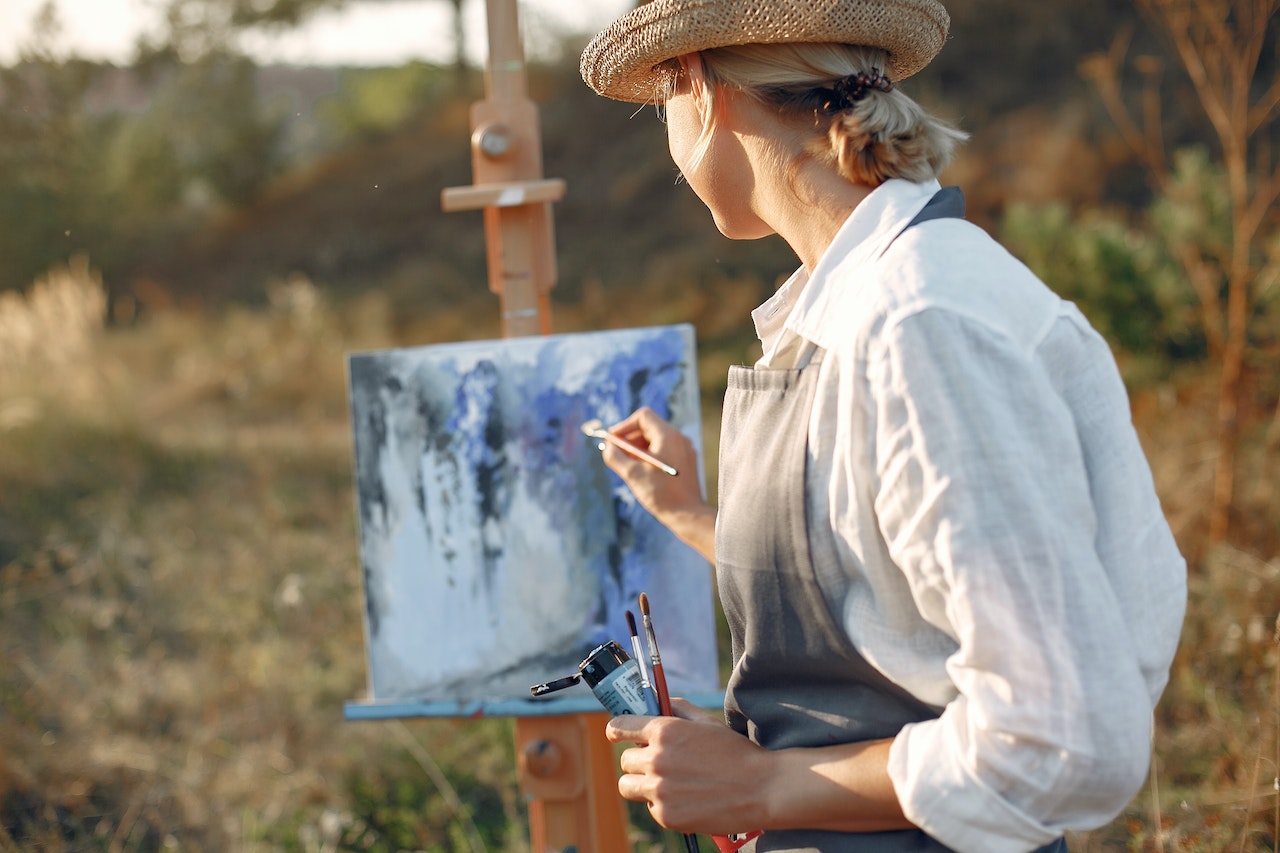 How to Find the Artist Residency That's Right for You. A woman paints a beautiful landscape painting.